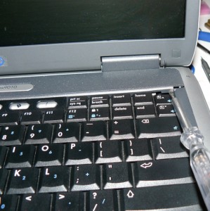 Removing the keyboard cover with a screwdriver